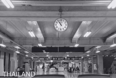 A black and white image of Suvarnabhumi Airport interior showing clock, seating area, and passengers in Bangkok