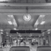 A black and white image of Suvarnabhumi Airport interior showing clock, seating area, and passengers in Bangkok