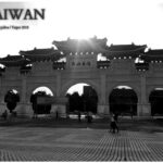 Liberty Square Arch in Taipei, Taiwan, with five arched gateways, ornate roof structures, and Chinese characters for Liberty Square, silhouetted against the sunset with people walking.