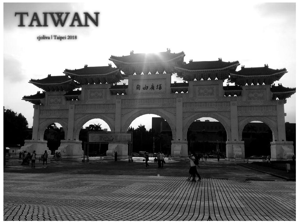 Liberty Square Arch in Taipei, Taiwan, with five arched gateways, ornate roof structures, and Chinese characters for Liberty Square, silhouetted against the sunset with people walking.