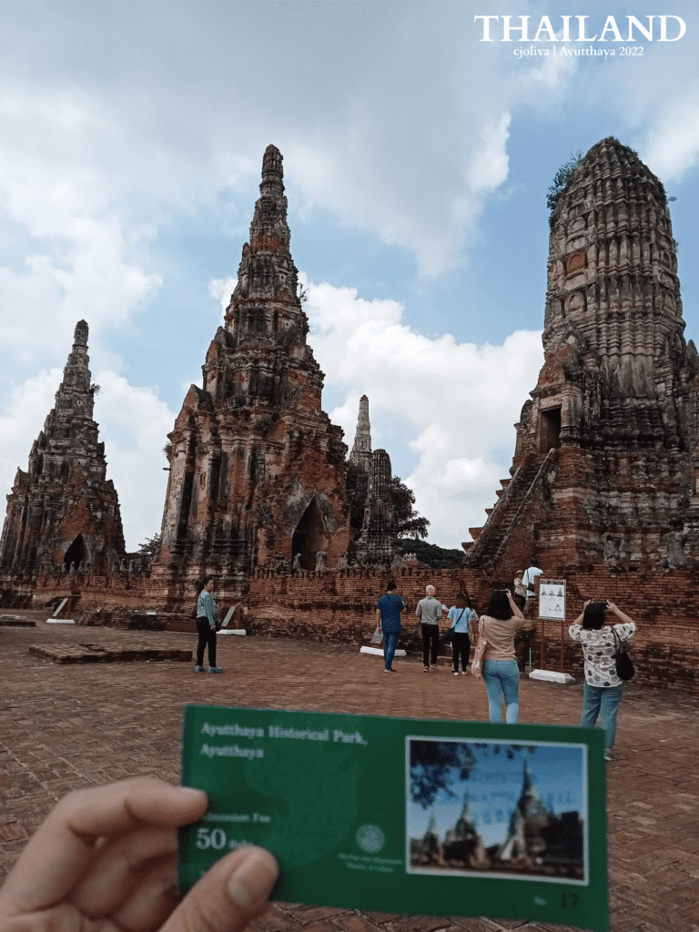 A visitor holding an entrance ticket at Ayutthaya Historical Park with ancient temple ruins in the background, Thailand