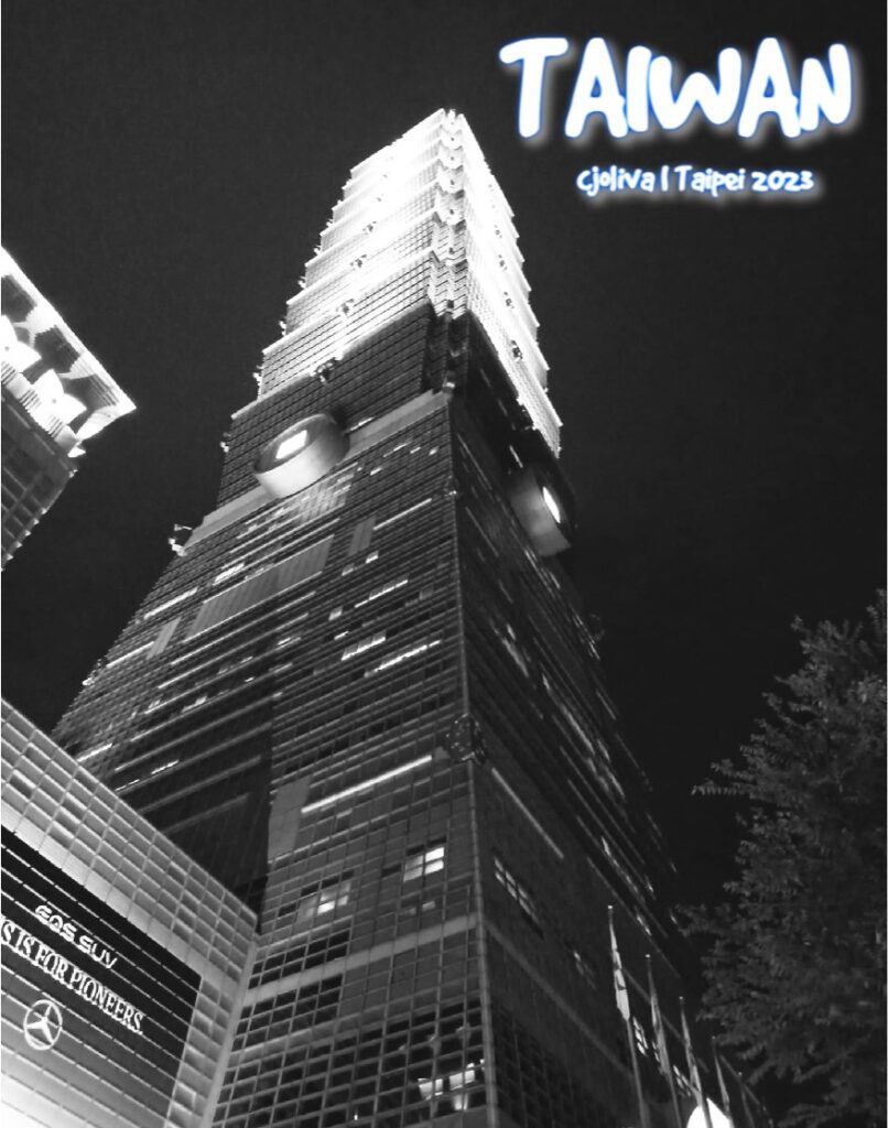 A low-angle, black and white photograph of the Taipei 101 skyscraper illuminated against a dark night sky, showcasing its iconic tiered architectural design and the surrounding city lights in Taipei, Taiwan.
