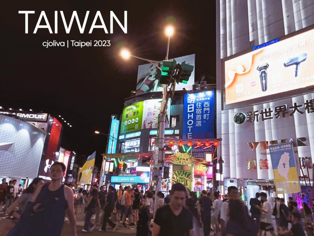 A bustling night scene in Ximending, Taipei, featuring glowing neon billboards, large digital advertisements, and a crowd of people walking through the pedestrian shopping district under bright streetlights.