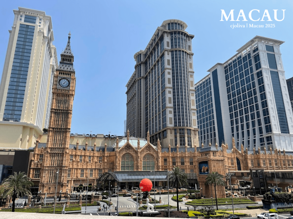 A wide view of The Londoner Macao resort, featuring a full-scale replica of the Elizabeth Tower (Big Ben) and the Houses of Parliament architecture, flanked by modern hotel towers under a clear sky.