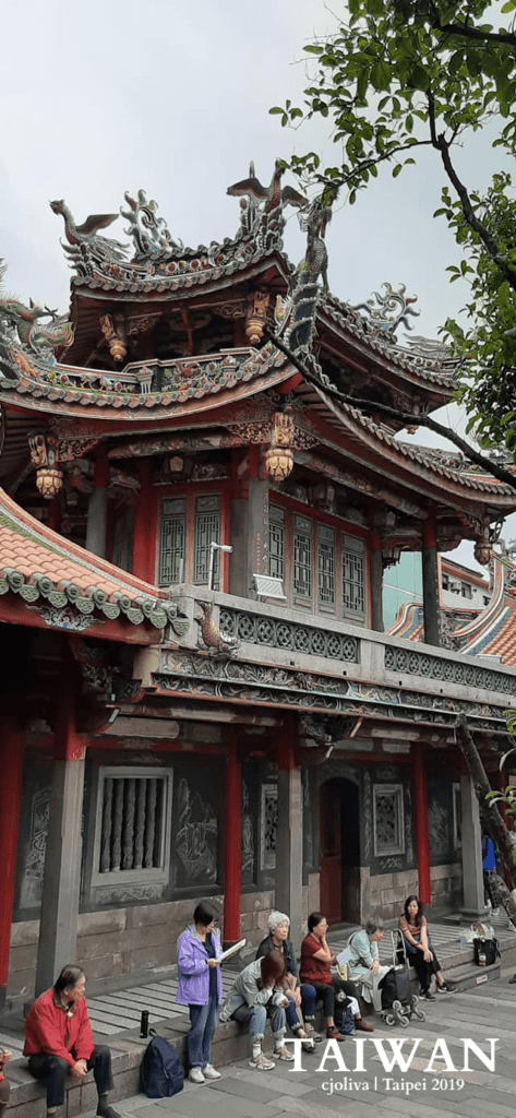 Longshan Temple with ornate carvings, dragon and phoenix roof sculptures, and red columns in Taipei, Taiwan.