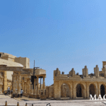 Classical Roman-style stone arches and columns at Macau Fisherman's Wharf under a clear blue sky.