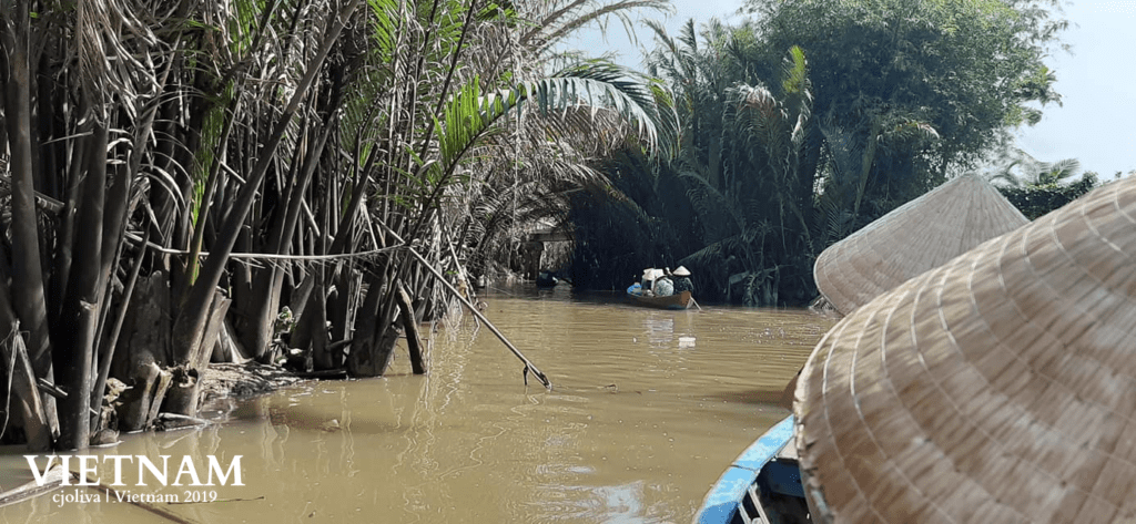 Traditional boat ride on a narrow waterway during a Mekong River Delta Tour in Vietnam