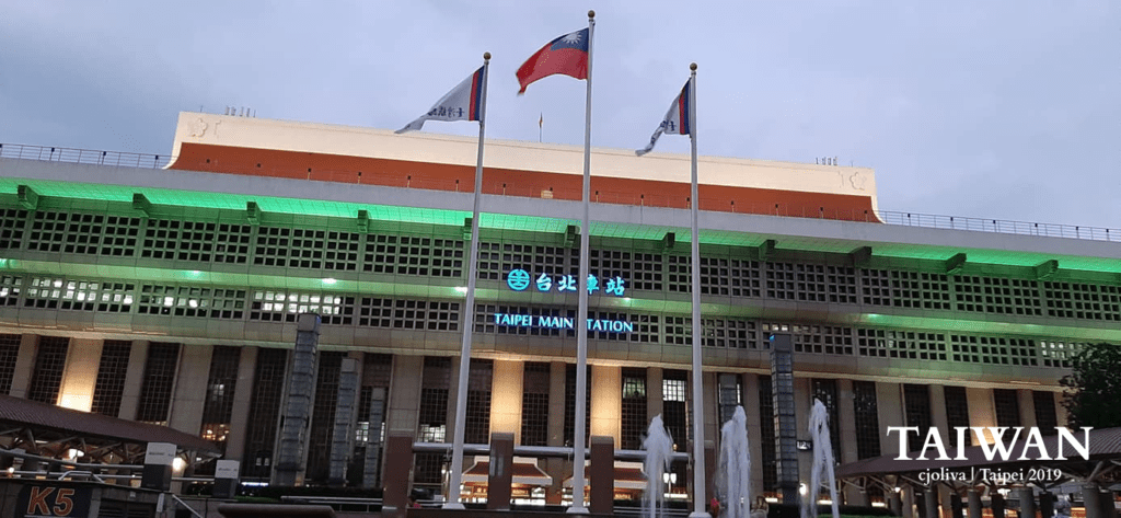 Taipei Main Station facade at night with illuminated signage and flagpoles in Taipei, Taiwan.