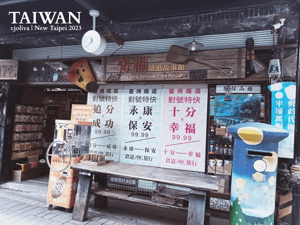 Exterior of Jingtong Railway Story House in New Taipei, Taiwan, featuring a rustic wooden storefront, traditional Chinese signage, a vending machine, a painted mailbox, and railway‑themed decorations.
