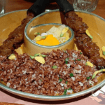 Vietnam Street Food and Culture were showcased in a traditional ceramic bowl with grilled meat skewers, rice garnished with herbs and petals, and pickled vegetables at Bếp Nhà Lục Tỉnh restaurant.