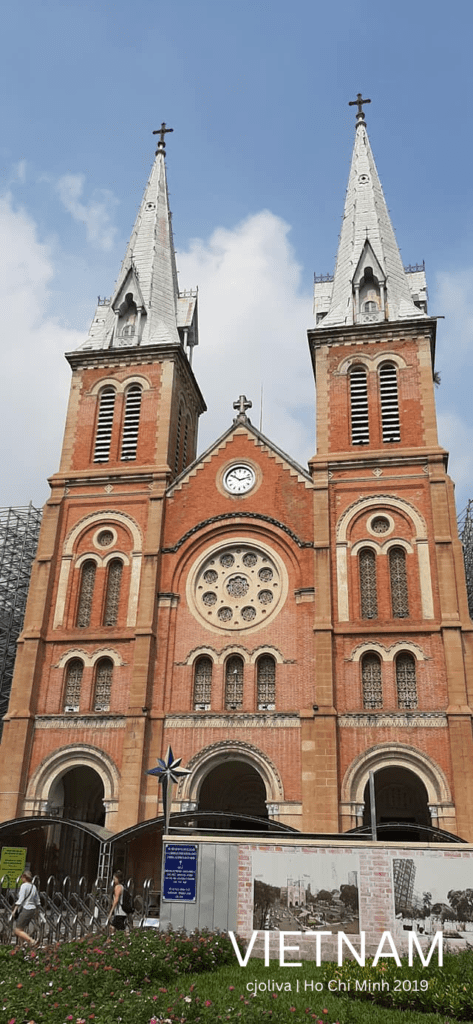 Vietnam Street Food and Culture are connected to heritage at the Notre-Dame Cathedral Basilica of Saigon, featuring twin bell towers, a red brick façade, and French colonial design in Ho Chi Minh City.