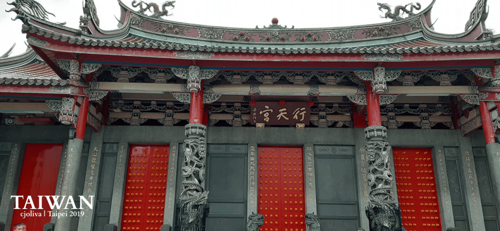 Xingtian Temple front façade with red pillars, dragon carvings, and ornate roof decorations in Taipei, Taiwan.
