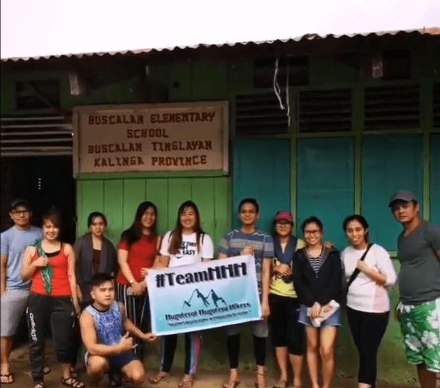 A group of people are posing in front of Buscalan Elementary School, holding a banner that reads "#TeamHHH Hugoterot Hugotera Hikers" in Buscalan, Kalinga Province.