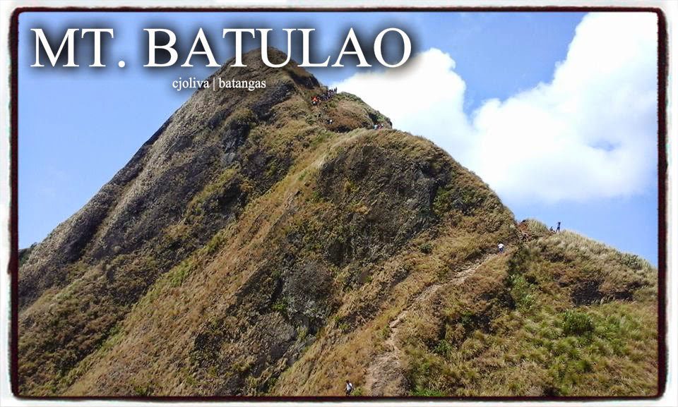 Steep rocky peak of Mt. Batulao with hikers climbing on the narrow trail under blue sky