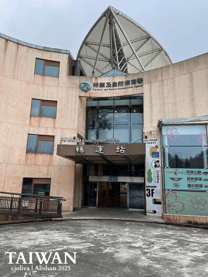 The modern Alishan Transport Station in Taiwan with canopy roof, glass doors, and signage noting elevation of 2,408 meters