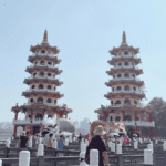 The famous twin seven-story Dragon and Tiger Pagodas at Lotus Pond in Kaohsiung, Taiwan, with tourists walking along the bridge.