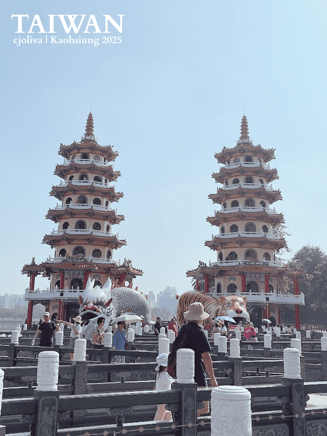 The famous twin seven-story Dragon and Tiger Pagodas at Lotus Pond in Kaohsiung, Taiwan, with tourists walking along the bridge.