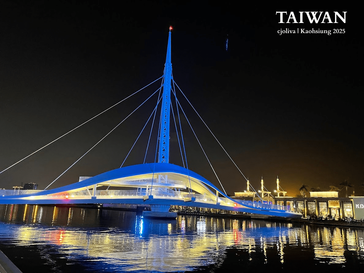 Night view of the Great Harbor Bridge (Dagang Bridge) in Kaohsiung, Taiwan. The white cable-stayed bridge is illuminated in blue, reflecting on the water near Pier-2.