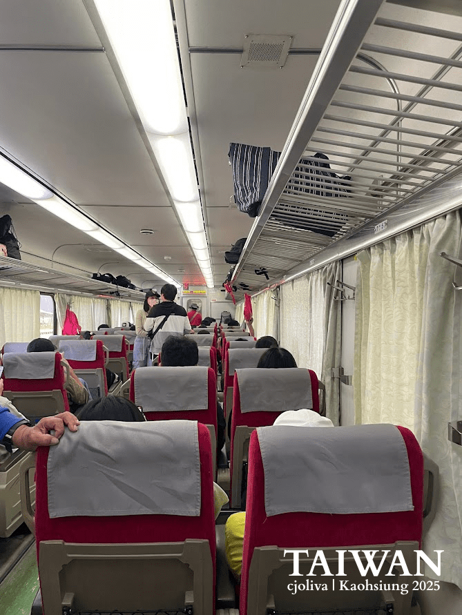 Interior view of a Taiwan Railways (TRA) passenger train car with red cushioned seats and cream-colored curtains, showing passengers seated during a journey to Kaohsiung.