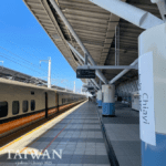 Modern train station in Chiayi, Taiwan with sleek high-speed train on platform 5 under angular roof and white beams