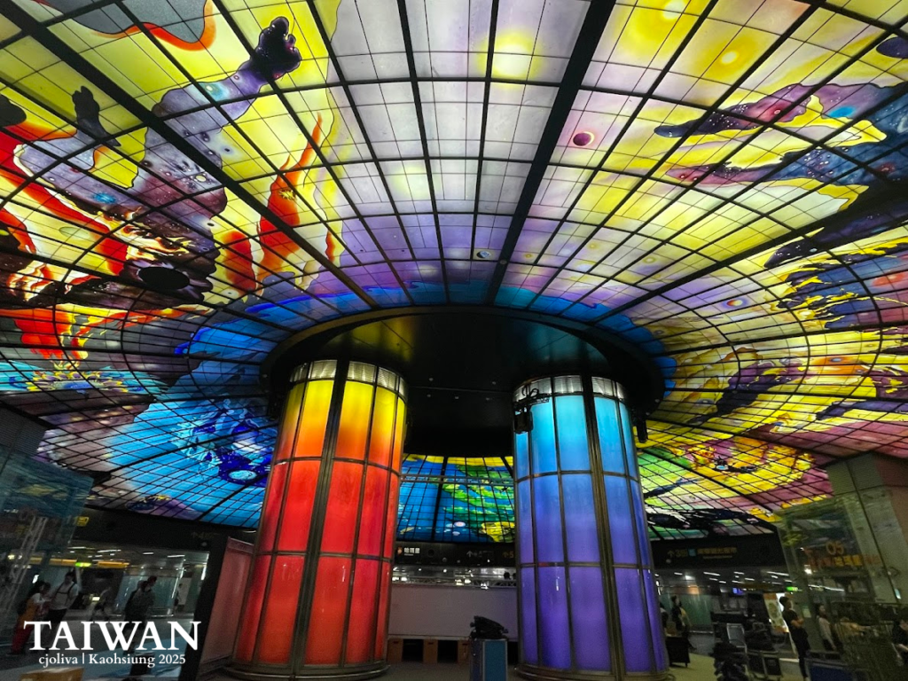 Wide-angle shot of the Dome of Light stained-glass ceiling at Formosa Boulevard Station, Kaohsiung, featuring the iconic blue and red illuminated pillars.