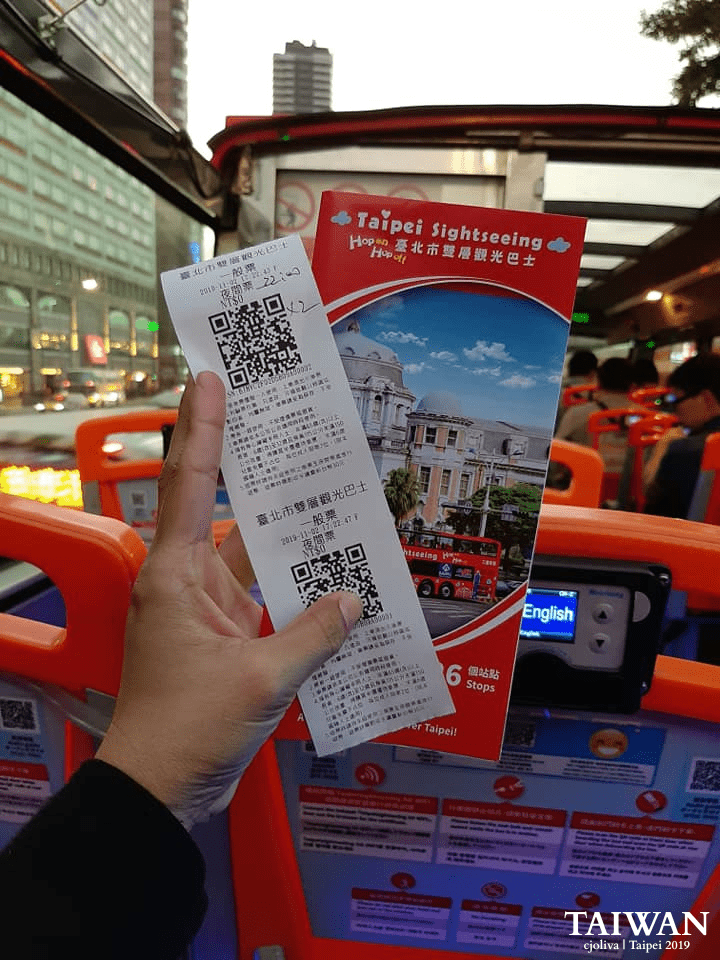 Tourist holding hop-on hop-off bus ticket and brochure inside a sightseeing bus in Taipei, Taiwan.