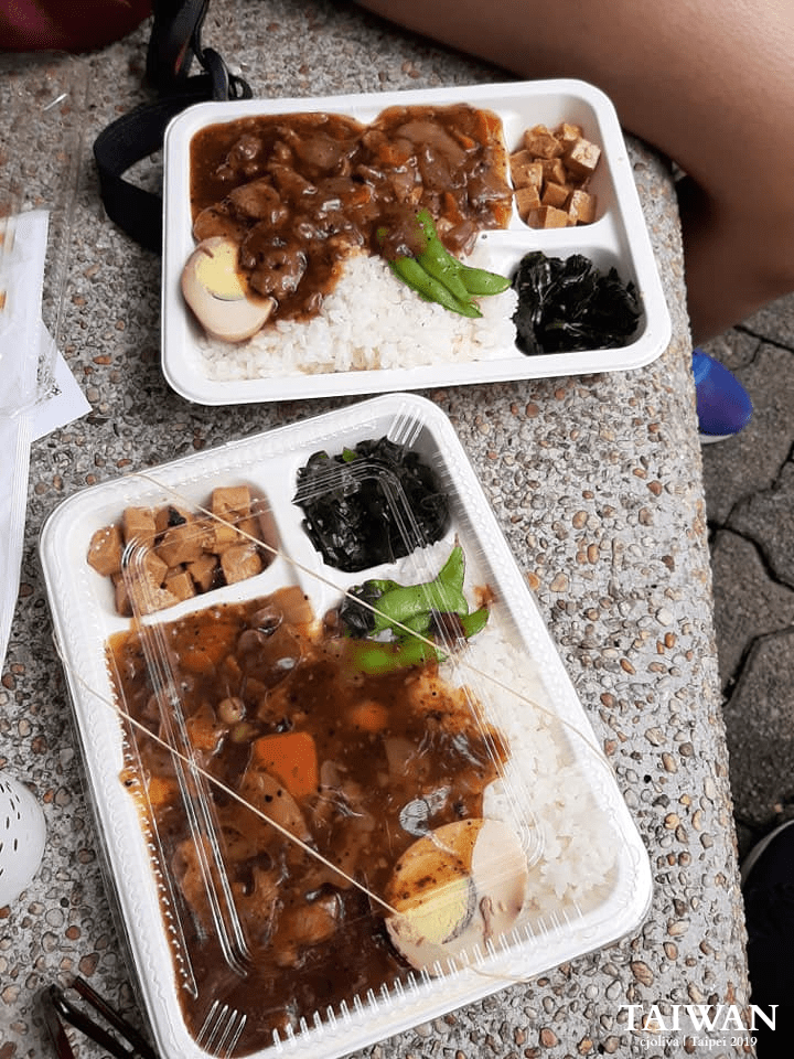 Taiwanese bento meals with rice, meat, vegetables, tofu, and egg in containers outdoors in Taipei.