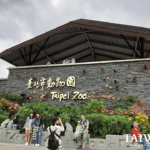 The Taipei Zoo entrance in Taipei, Taiwan, with gold lettering, festive decorations, and visitors in front.