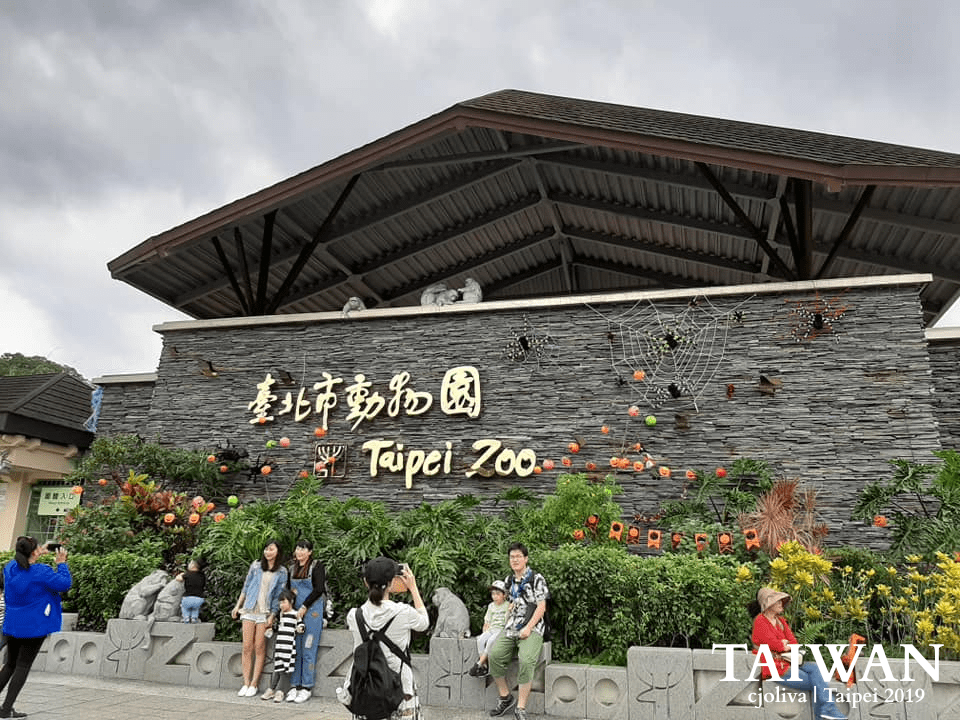 The Taipei Zoo entrance in Taipei, Taiwan, with gold lettering, festive decorations, and visitors in front.