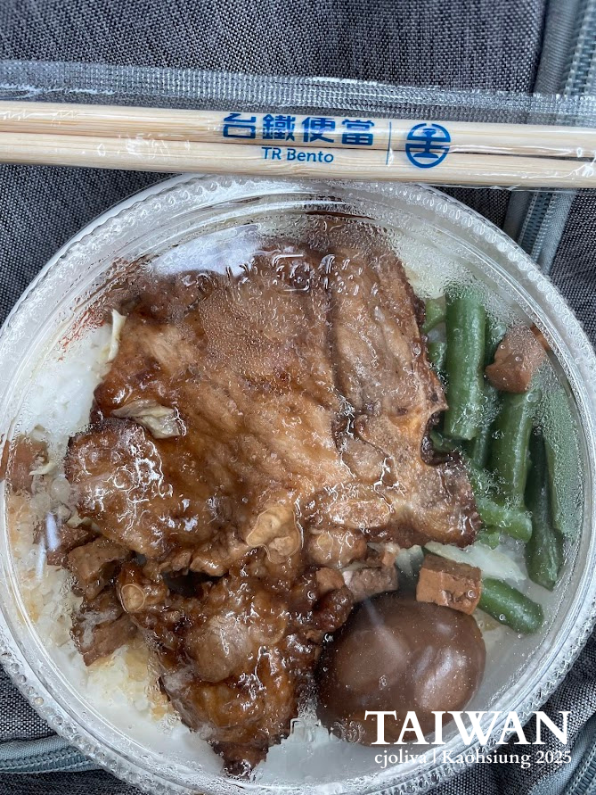 Close-up of a classic Taiwan Railway (TR) Bento box with braised pork, green beans, and a soy egg, with official branded chopsticks on top.