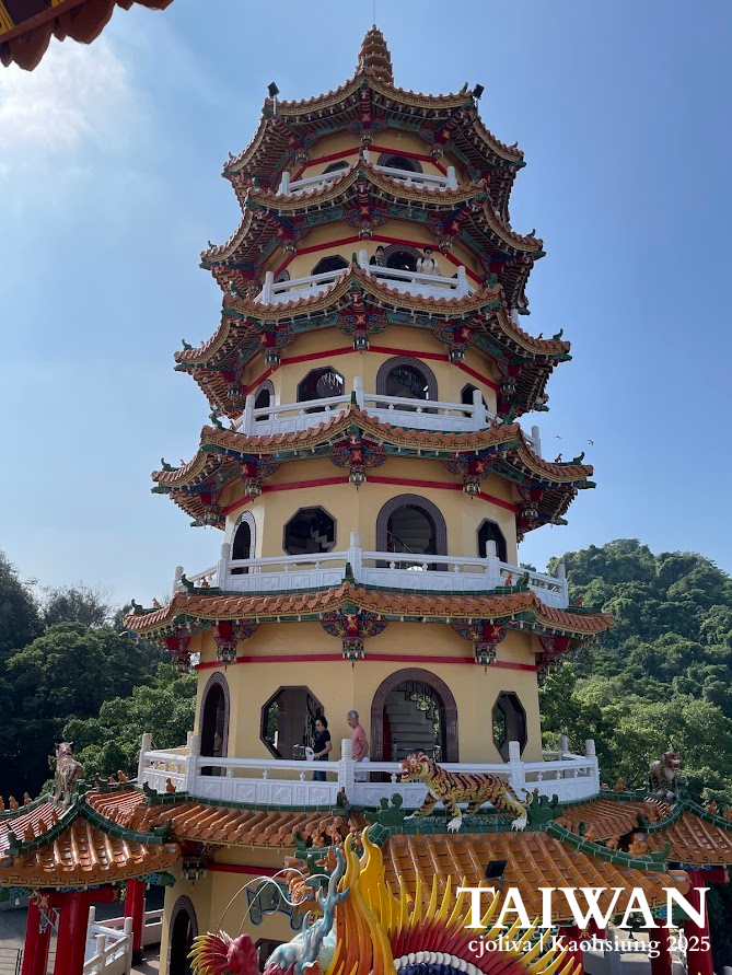 Vertical view of the seven-story Tiger Pagoda in Kaohsiung, Taiwan, featuring yellow walls, red pillars, and small tiger statues on the roof tiles.