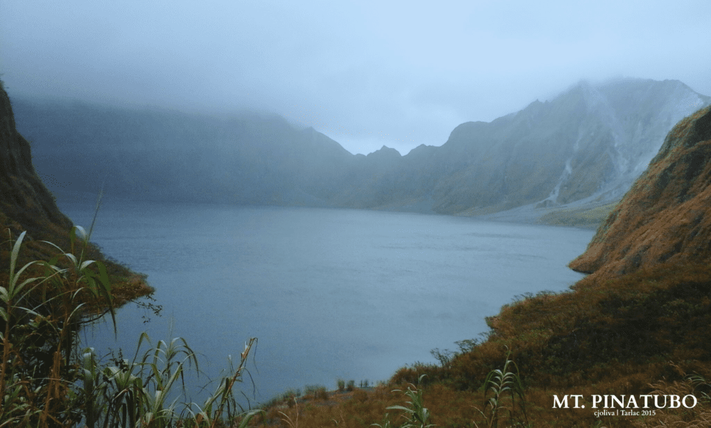 Misty view of the crater lake at Mt. Pinatubo surrounded by steep rocky slopes and vegetation in Tarlac, 2015.