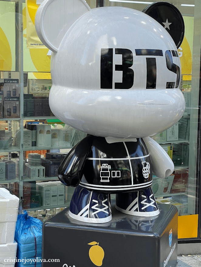 A large white and black "BTS" bear statue standing outside a store in Myeongdong, Seoul.