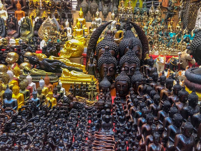 A dense collection of gold and bronze Buddha figurines and statues at a market in Bangkok.