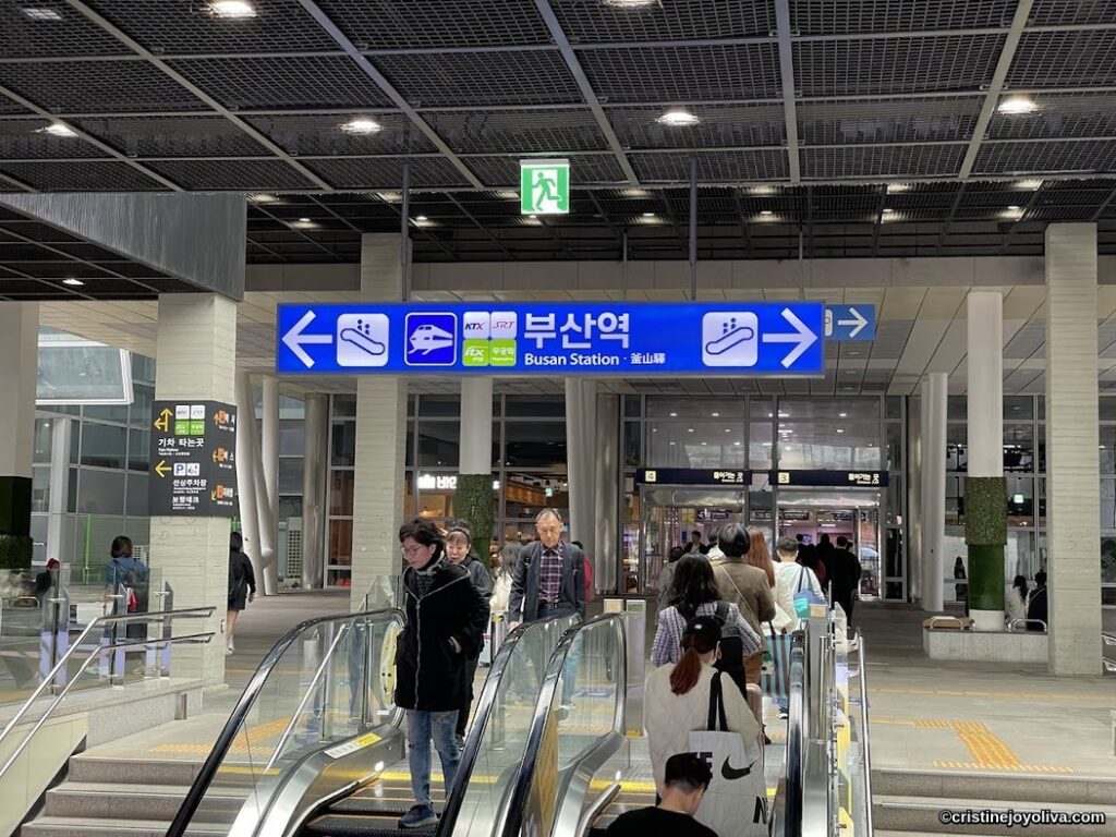 Busan Station entrance with escalators and directional signs in Korean and English