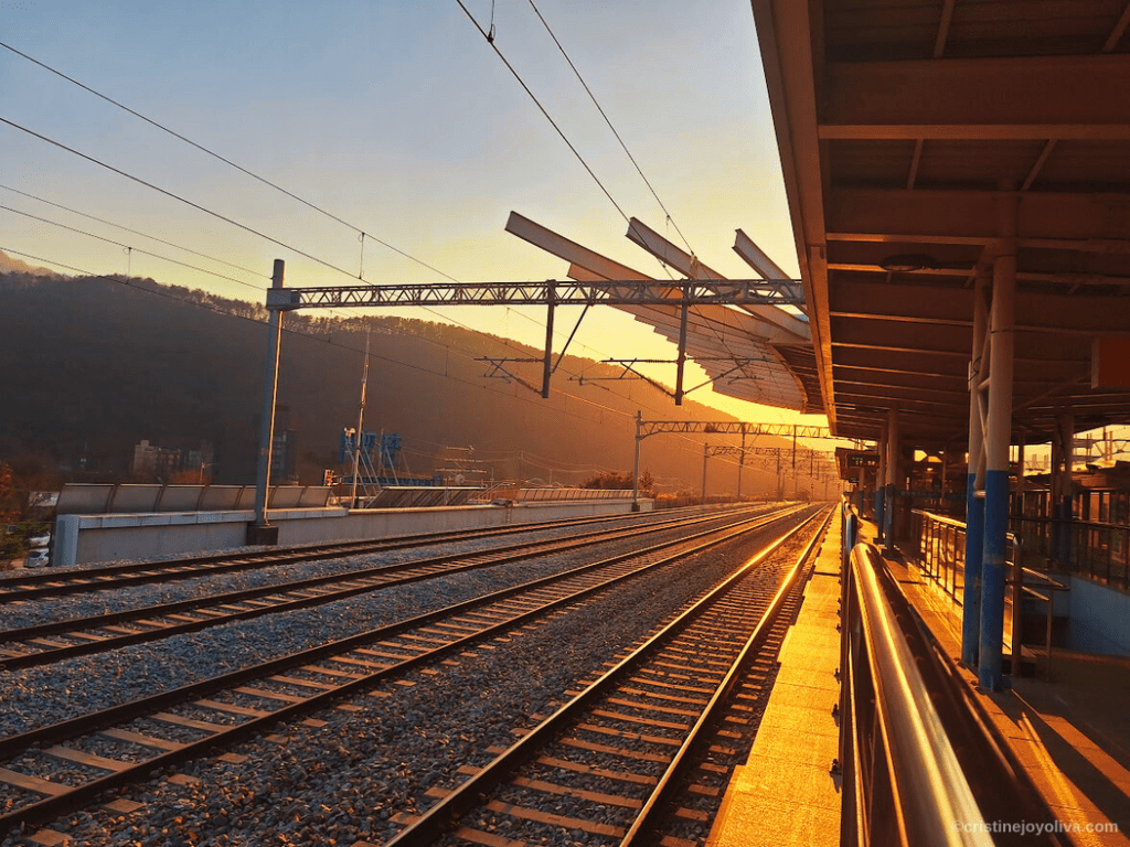 Golden sunset over Cheongpyeong railway station platform with parallel tracks and overhead lines