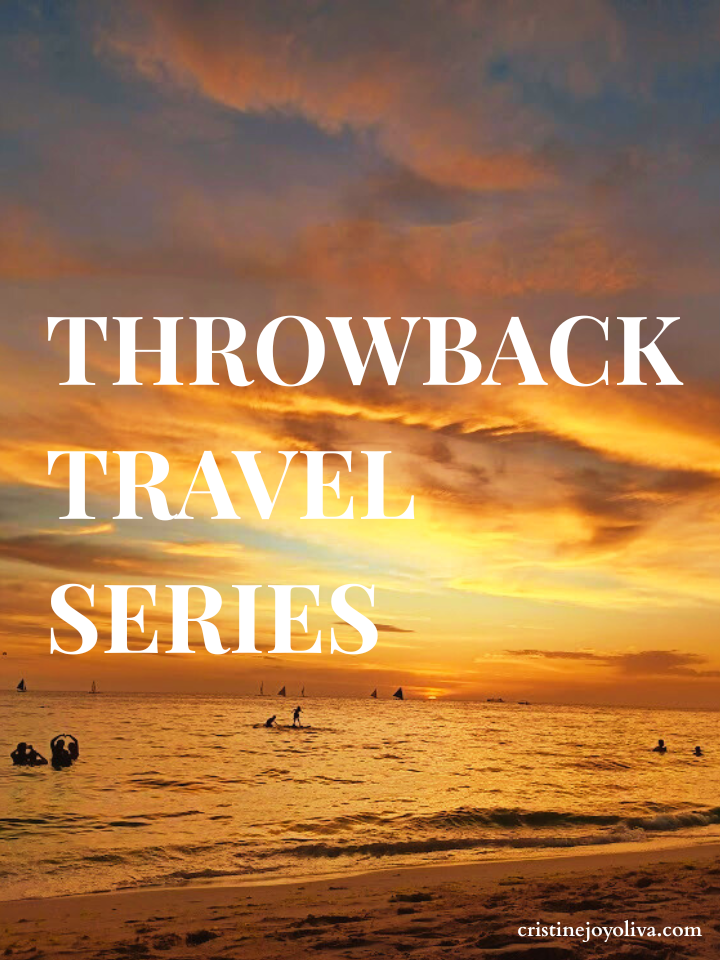 Silhouetted people swimming and paddleboarding in Boracay’s White Beach during a vibrant golden orange sunset with paraw sailboats on the horizon.