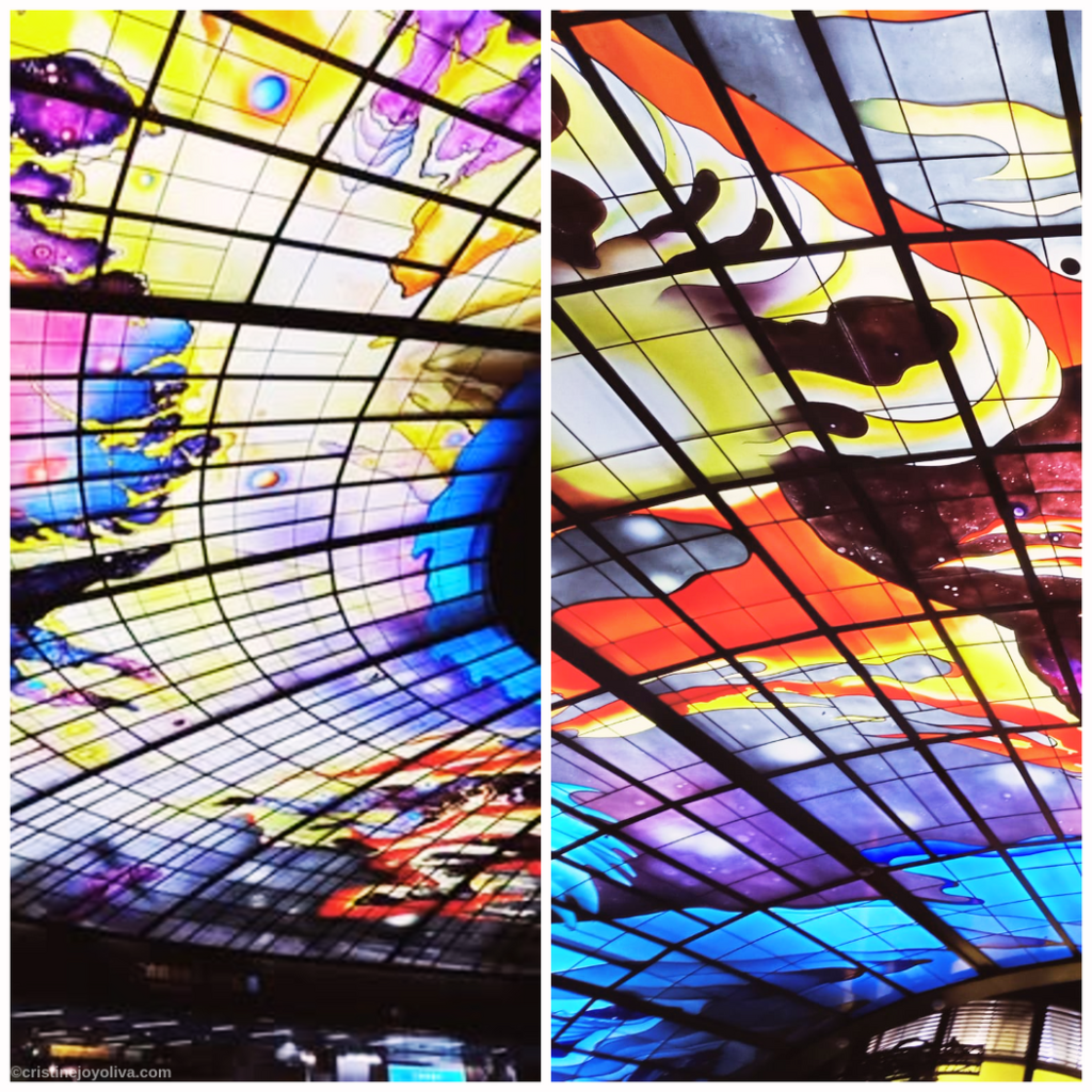 A close-up split view of the Dome of Light at Formosa Boulevard Station in Kaohsiung, Taiwan, featuring vibrant stained-glass ceiling panels with intricate cosmic and elemental designs.