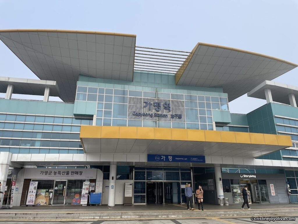 Exterior view of Gapyeong Station in South Korea, a modern Korail railway hub with glass facade and local specialty shops.