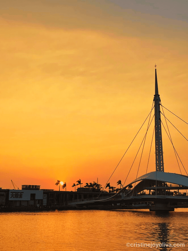 Sunset over Great Harbor Bridge in Kaohsiung, Taiwan with reflections on the water