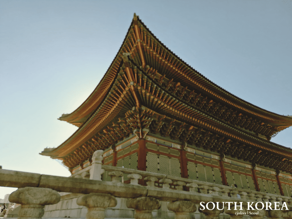Gyeongbokgung Palace traditional Korean architecture with intricate green and red woodwork under a clear sky in Seoul.