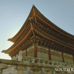 Gyeongbokgung Palace traditional Korean architecture with intricate green and red woodwork under a clear sky in Seoul.