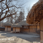 Cluster of traditional Korean thatched-roof houses with clay walls and wooden beams at Korean Folk Village in Gyeonggi-do, South Korea, 2023