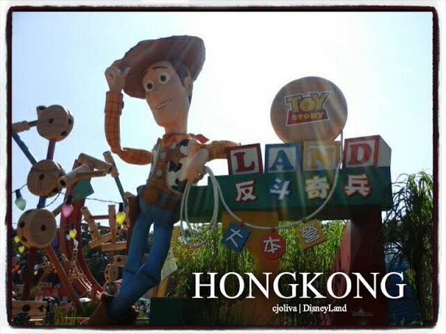 A large Woody statue tipping his hat at the entrance to Toy Story Land in Hong Kong Disneyland, with colorful oversized toys and playful decorations.