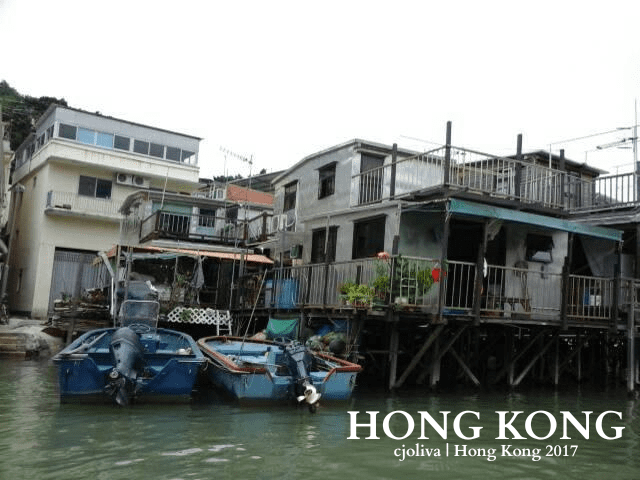 Traditional stilt houses in Tai O, Hong Kong, built above the water with boats docked nearby and plants on balconies.