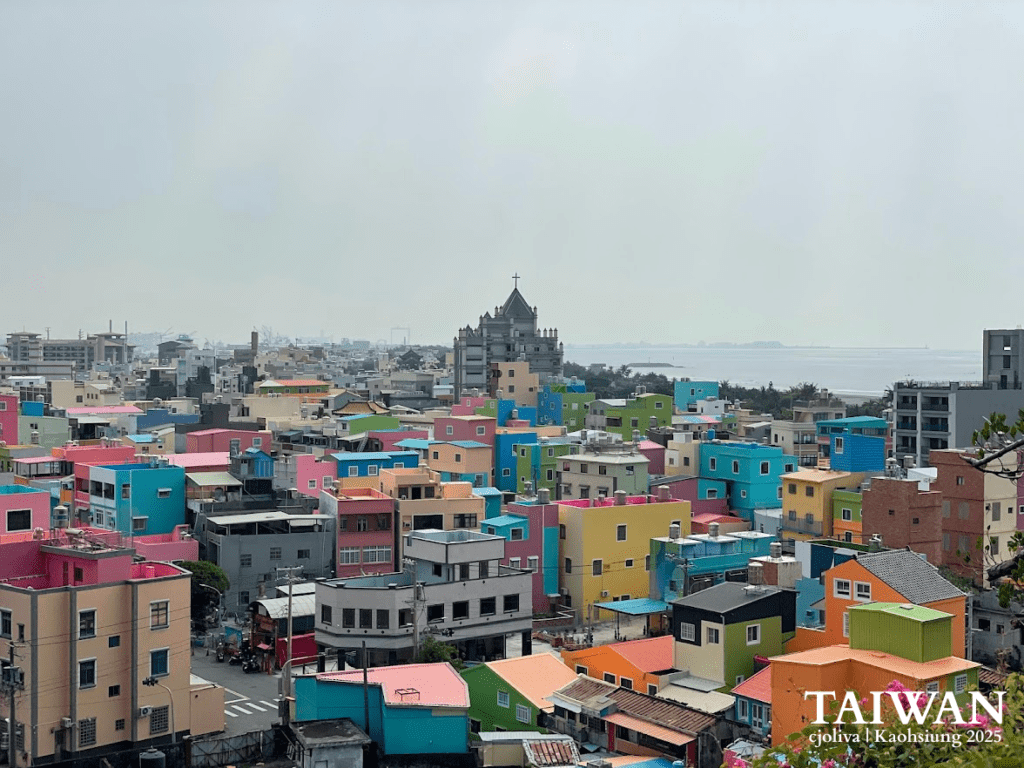 Brightly painted urban neighborhood with pink, blue, yellow, and green buildings, church with cross, and coastline in Kaohsiung, Taiwan
