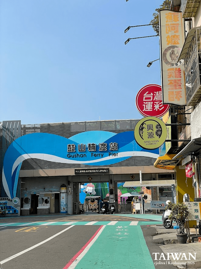 Entrance to Gushan Ferry Pier in Kaohsiung, Taiwan with wave mural, ticket machines, and scooters parked nearby