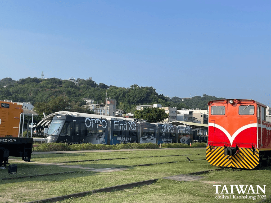 A modern Kaohsiung Light Rail tram passing by a vintage red and yellow diesel locomotive at Hamasen Railway Museum