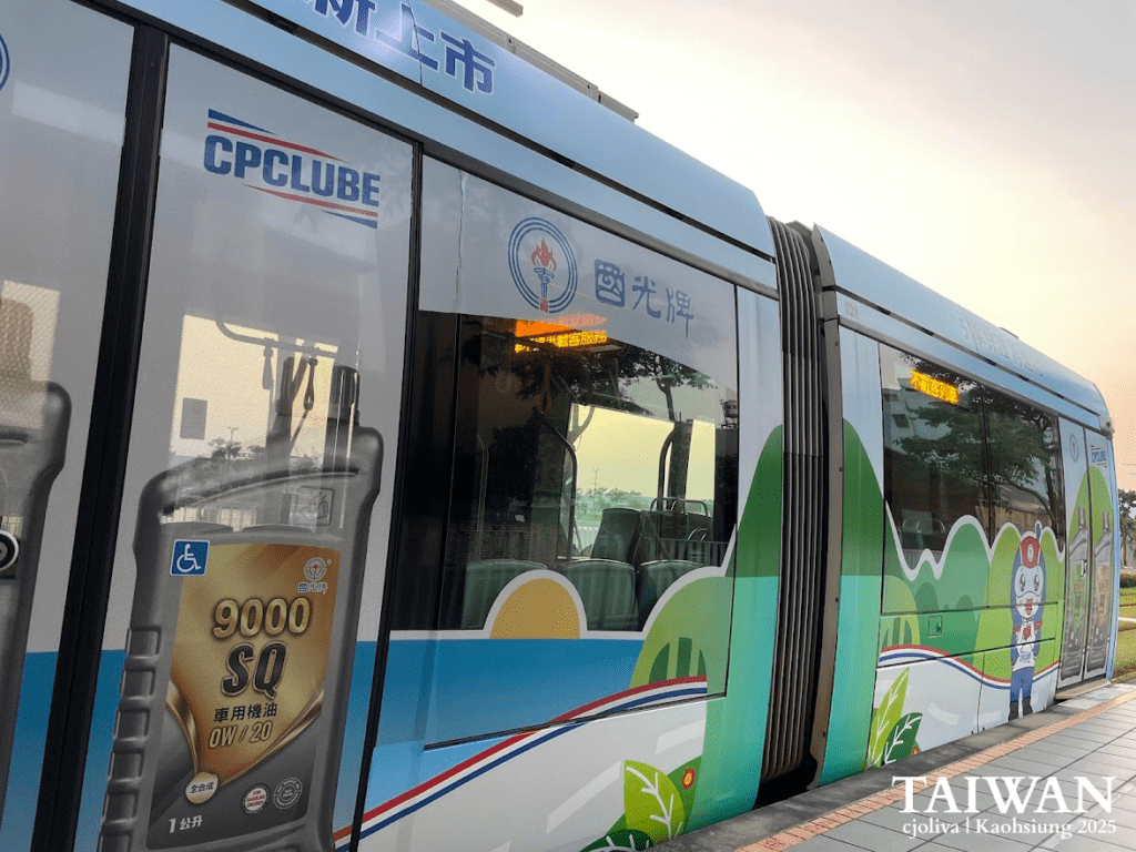 Close-up of a modern Kaohsiung Light Rail tram with colorful commercial advertisements at a station platform during sunset