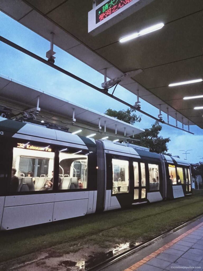 Kaohsiung light rail tram at dusk with passengers boarding after rain in Taiwan